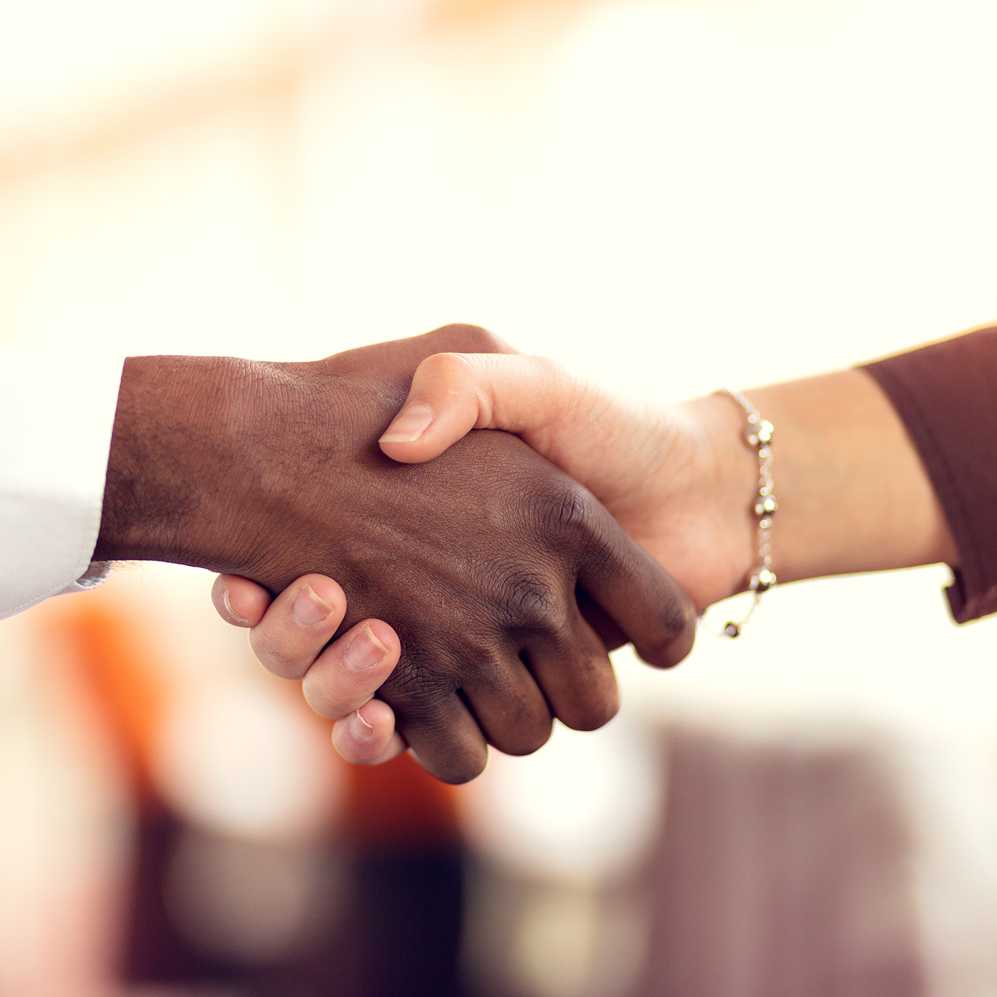 Closeup of White and Black shaking hands over a deal.